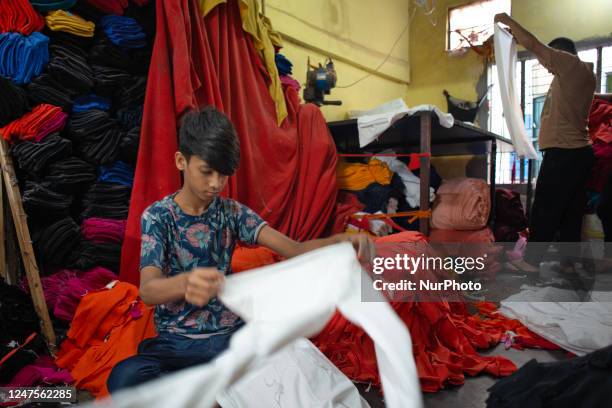 Child labour working besides his elderly colleagues in a local garment factory outtake the capital Dhaka, Bangladesh on February 28, 2023.