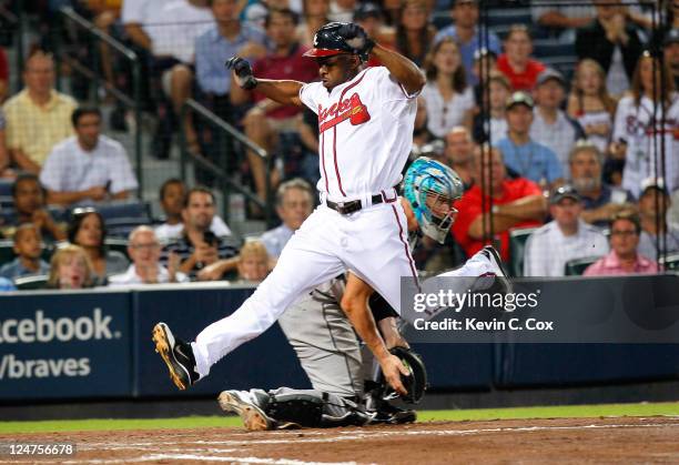 Michael Bourn of the Atlanta Braves leaps over the throw to catcher John Buck of the Florida Marlins as he scores in the fifth inning at Turner Field...