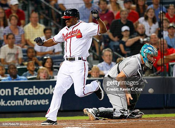 Michael Bourn of the Atlanta Braves leaps over the throw to catcher John Buck of the Florida Marlins as he scores in the fifth inning at Turner Field...