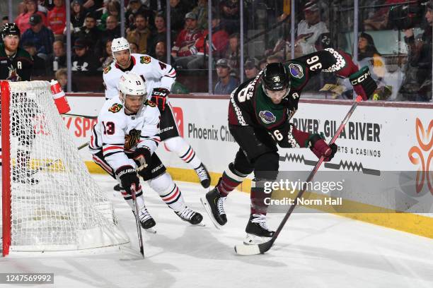 Christian Fischer of the Arizona Coyotes skates with the puck while being defended by Max Domi of the Chicago Blackhawks during the first period at...