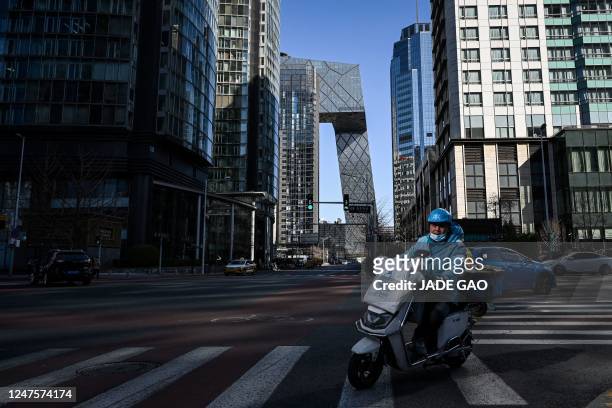 Delivery driver rides a through the central business district in Beijing on March 1, 2023.