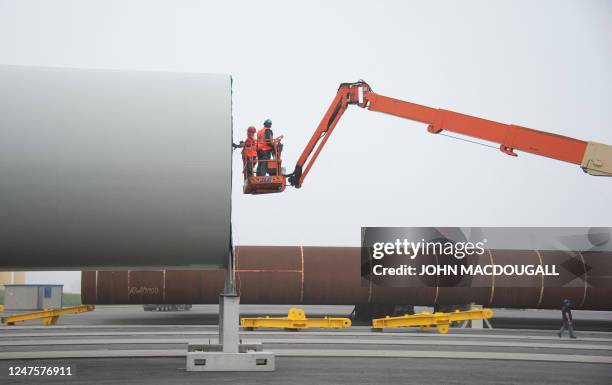 Workers prepare the section of a wind turbine steel tower for transport at the offshore terminal of the Offshore Base Cuxhaven June 7, 2011....