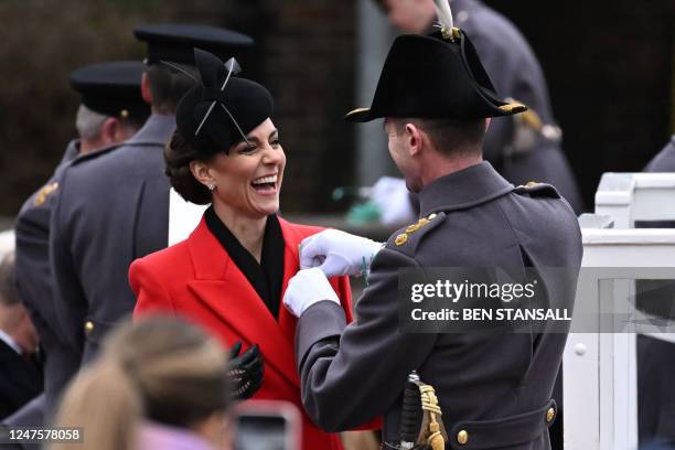 Britain's Catherine, Princess of Wales, laughs as she is pinned a leek onto her coat during a visit to the 1st Battalion Welsh Guards for St David's...