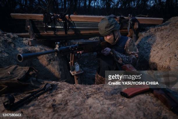 Member of a Ukrainian volunteer unit and a computer science student Valdemar poses with the unit's soviet-era DP27 machine gun in a trench used to...