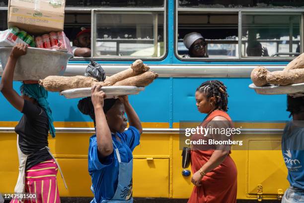 Street vendors pass a stationary bus in the Makola district of Accra, Ghana, on Tuesday, Feb. 28, 2023. Ghanas cedi, the worlds second-worst...