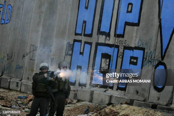 An Israeli soldier fires a tear gas canister at Palestinian stone-throwers during clashes which erupted following a demonstration supporting the Gaza...