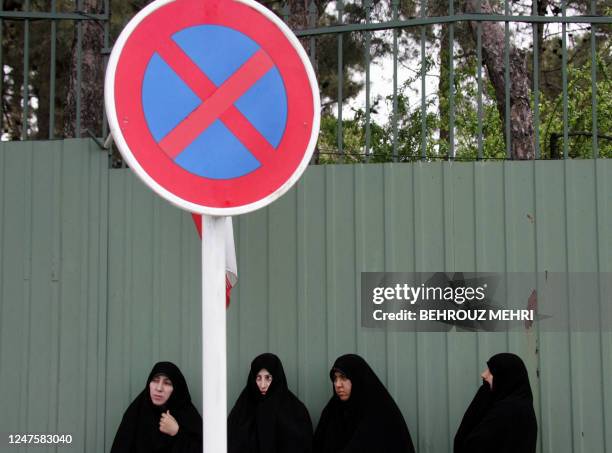 Iranian students stand behind a 'no stopping' road sign during a gathering in support of Iran's nuclear program outside Iran's Atomic Energy...