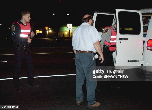 Fairfax County Police Officers search a white van at a roadblock on route 50 after a woman was fataly shot evening at a Home Depot parking lot near...