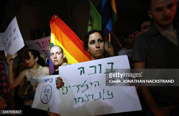 An Israeli woman holds a sign that reads in Hebrew: "crys for the children that got murderd," during a demonstration at the scene of a shooting at a...