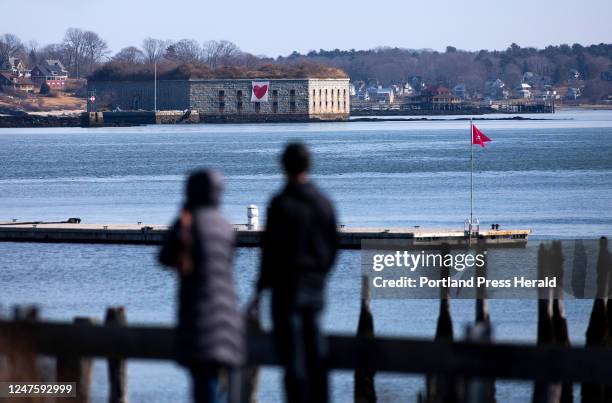 Couple stop to take in the view across Casco Bay, where a large Valentine's Day banner hangs from Fort Gorges on Hog Island Ledge.