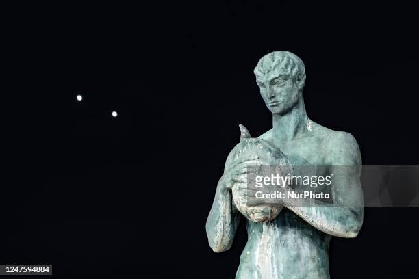 Planets Jupiter and Venus in conjunction are seen after sunset behind a statue in LAquila, Italy, on march 1st, 2023. Planets seem to be very close ....