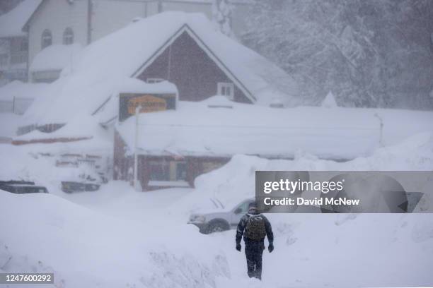 Man walks through falling snow as residents throughout the San Bernardino Mountains continue to be trapped in their homes on March 1, 2023 in Running...