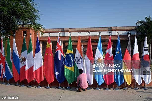 Man arranges the national flags of participating nations during the G20 foreign ministers' meeting in New Delhi on March 2, 2023.