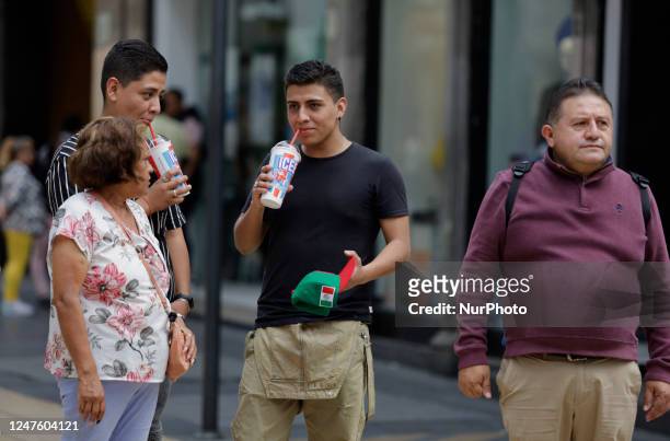 Group of people consume flavoured carbonated snow and ice cream in the streets of Mexico City. Whether with water, under the shade, soft drinks, ice...