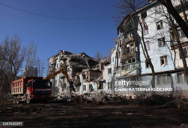 Ukrainian rescuers work with an excavator on a five-storey residential building destroyed after a missile strike in Zaporizhzhia on March 2 amid the...