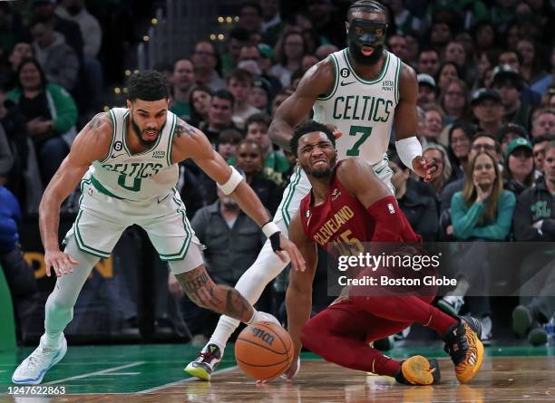 Cleveland Cavaliers SG Donovan Mitchell loses control of the ball as Boston Celtics SF Jayson Tatum dives forward to grab it. A masked Jaylen Brown...