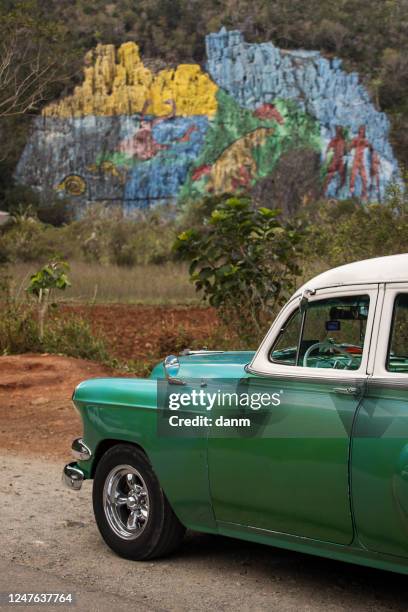 old american car with colourful mural wall from vinales, cuba - prehistoria stock pictures, royalty-free photos & images