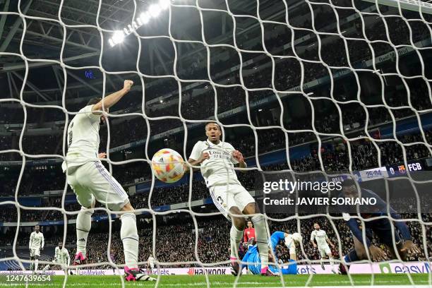 Real Madrid's Brazilian defender Eder Militao reacts after scoring an own-goal next to Barcelona's Ivorian midfielder Franck Kessie during the Copa...
