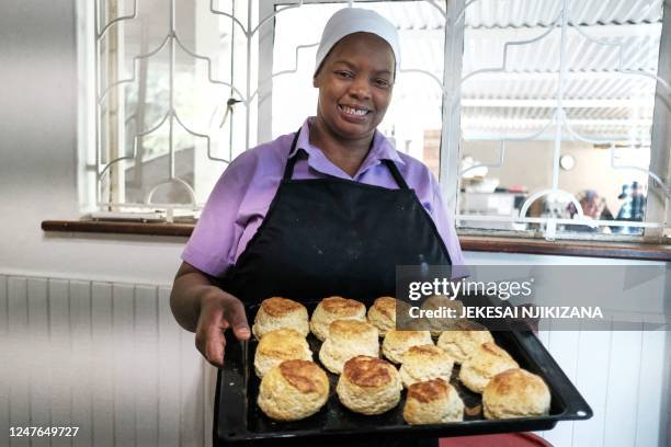 Veronica Makonese, a cook at Bottom Drawer, an upscale tearoom in Harare, displays freshly baked scones in Harare on February 16, 2023. - A sweet...