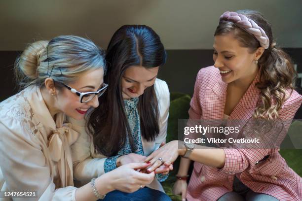 beautiful young woman showing off engagement ring in a cafe - aleksandra cvetkovic stock pictures, royalty-free photos & images