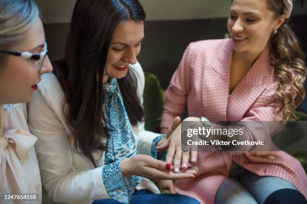 beautiful young woman showing off engagement ring in a cafe - aleksandra cvetkovic stock pictures, royalty-free photos & images