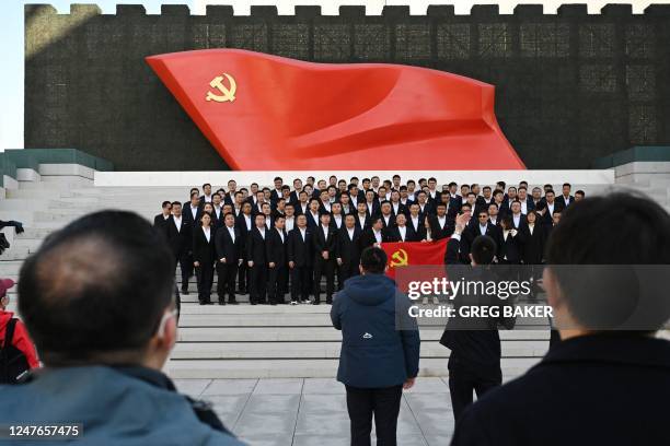 People pose for photos in front of the Chinese Communist Party flag during a visit to the Museum of the Communist Party of China in Beijing on March...