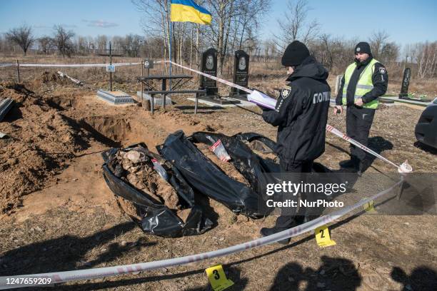 Image contains graphic content) Police officers inspect exhumed bodies from the mass grave of three civilians killed at the time of the Russian...