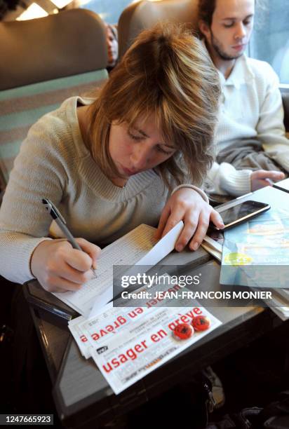 Une usager en "grève", Edwige Normand, remplit un coupon de retard à bord d'un train TGV reliant Le Mans à Massy, le 12 décembre 2011. Une...