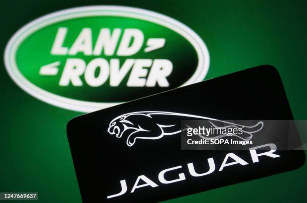 In this photo illustration, a Jaguar logo is seen on a smartphone and Land Rover logo on the background.