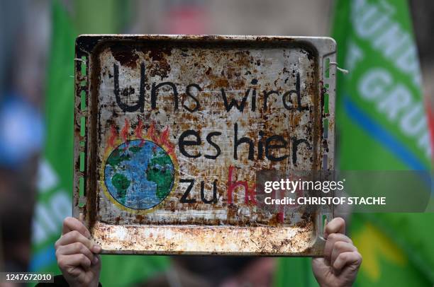 Supporter of the environmental Fridays for Future movement holds up a baking tray depicting the burning earth and reading "It's becoming too hot...