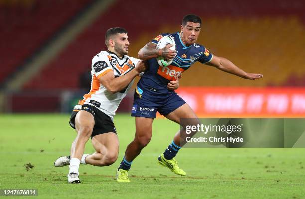 Erin Clark of the Titans is tackled by Adam Doueihi of the Tigers during the round four NRL match between the Gold Coast Titans and the Wests Tigers...