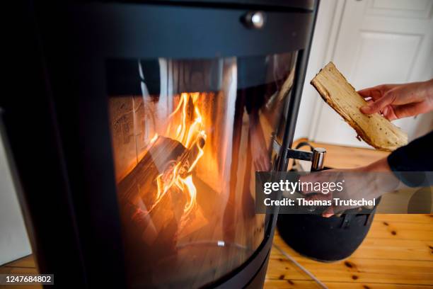 Woman throws a log into a wood stove on March 03, 2023 in Berlin, Germany.