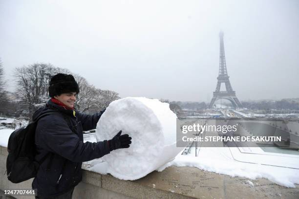 Man rolls snow on a Trocadero balcony in front of Eiffel tower on February 02, 2009 in Paris. Heavy snow disrupted transport across northern France...