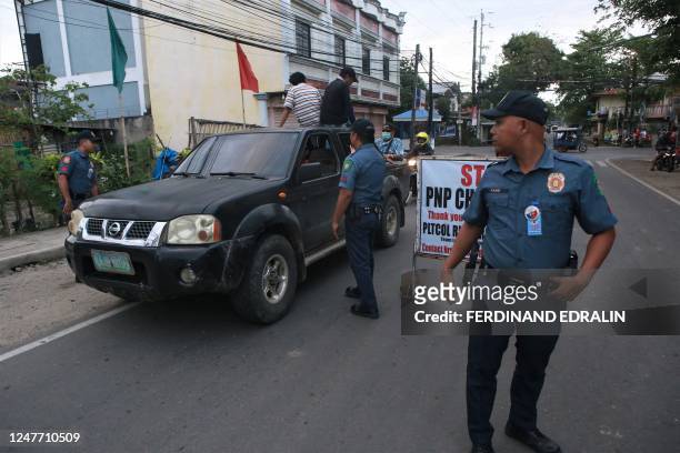 Policemen man a checkpoint between the border of Tanjay City and Pamplona town in the Philippine Province of Negros Oriental on March 4 hours after...