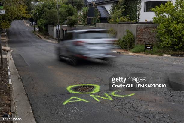 This picture shows a car speeding past a graffiti reading "ANC" in reference to the South African ruling party Africa National Congress next to a...