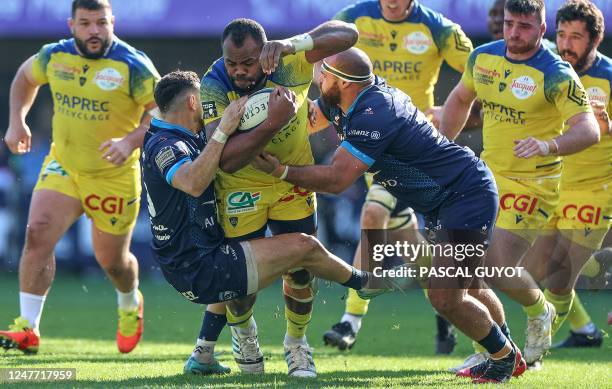 Clermont's Fijian flanker Peceli Yato is tackled by Montpellier's French prop Gregory Fichten and Montpellier's French centre Thomas Darmon during...