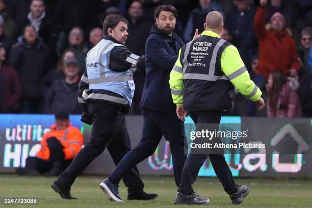Swansea City manager Russell Martin gives instructions to his players while being escorted off the pitch by security staff during the Sky Bet...