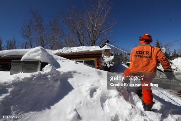 Cal Fire Fenner Canyon fire crew inmate drags snow off the roof of a residence at a Big Bear Lake trailer park as the area digs out following...