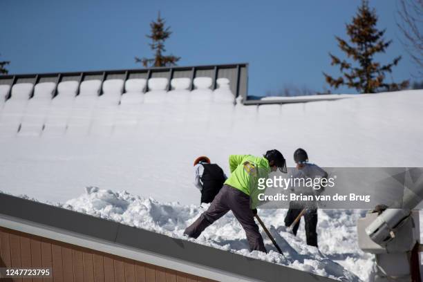 Employees of a tree care company shovel snow off the roof of a bank following successive storms which blanketed San Bernardino Mountain communities...
