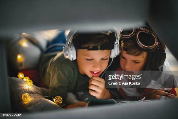 brothers using phone in the sofa fort. - kids fort stock pictures, royalty-free photos & images