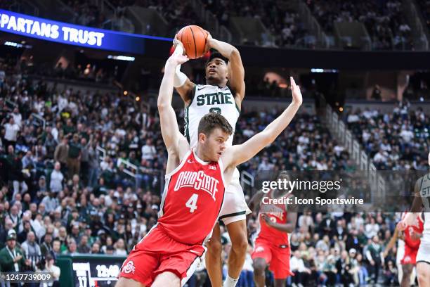 Michigan State Spartans guard Jaden Akins turns around Ohio State Buckeyes guard Sean McNeil as he shoots the ball during a college basketball game...