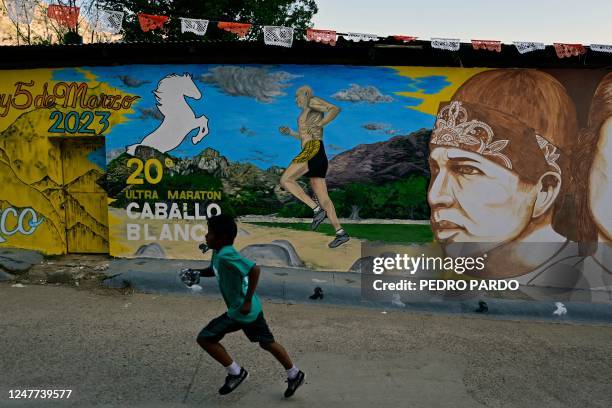 Raramuri runner jogs past a mural during the first day of activities of the ultra marathon Caballo Blanco in Urique , Chihuahua state, Mexico, on...