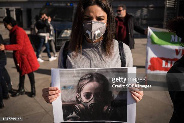Woman holds a placard with a drawing of a girl wearing gas masks in Iran during the demonstration. Iranian citizens residing in Spain, protest in...