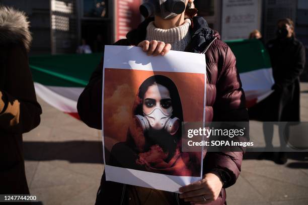 Woman holds a placard with a drawing of a girl wearing gas masks in Iran during the demonstration. Iranian citizens residing in Spain, protest in...