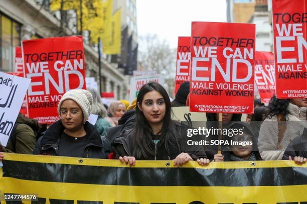 Women and girls hold a banner and placards expressing their opinion during the Million Women Rise protest in central London ahead of International...