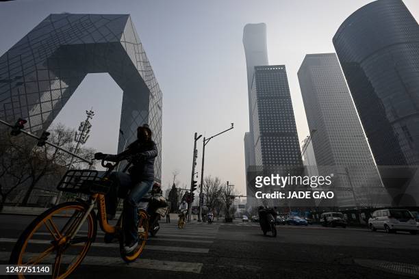 People ride bicycles along a street at central business district in Beijing on March 5, 2023