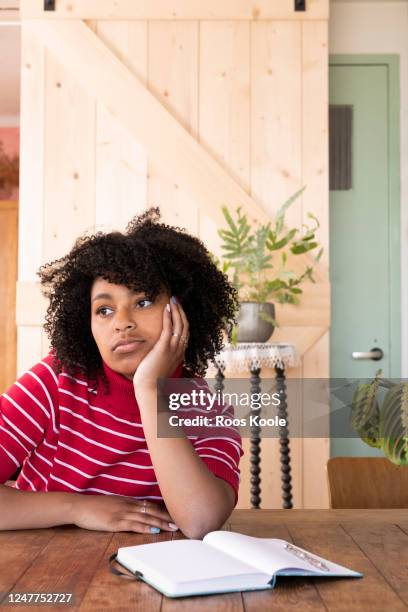 young woman sitting at a table - sighing stock pictures, royalty-free photos & images
