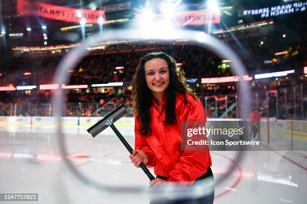 Calgary Flames ice girl cleans the plexiglass before the start of the third period of an NHL game between the Calgary Flames and the Minnesota Wild...