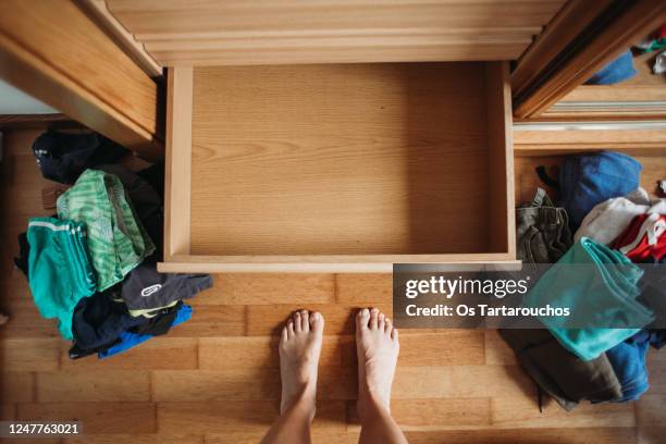 empty dresser drawer and messy clothes all over the floor before organizing - order vs chaos stock-fotos und bilder