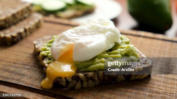 rye bread toast with avocado and poached egg - gepocheerd stockfoto's en -beelden